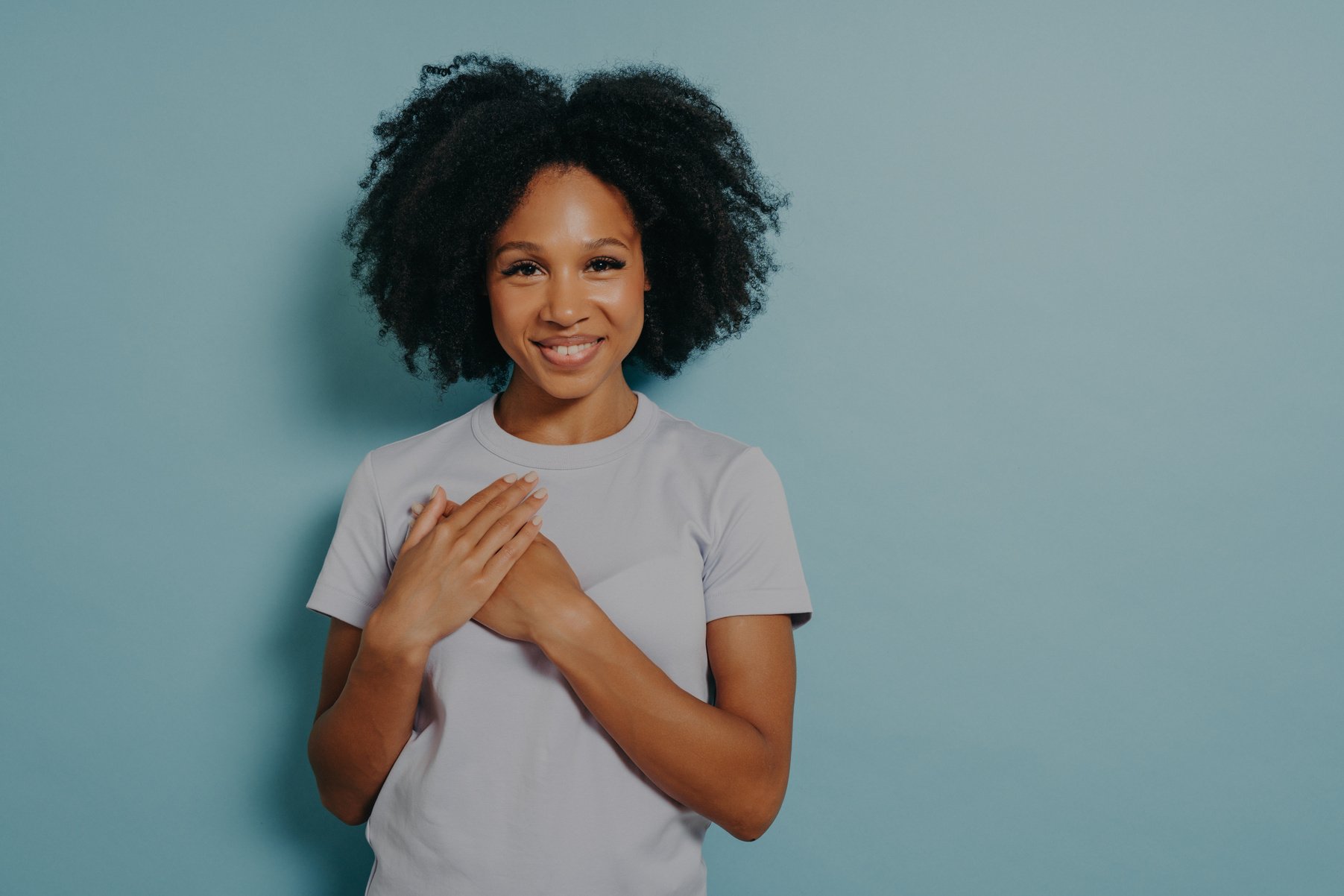 Grateful happy black woman holding hands on chest, satisfied